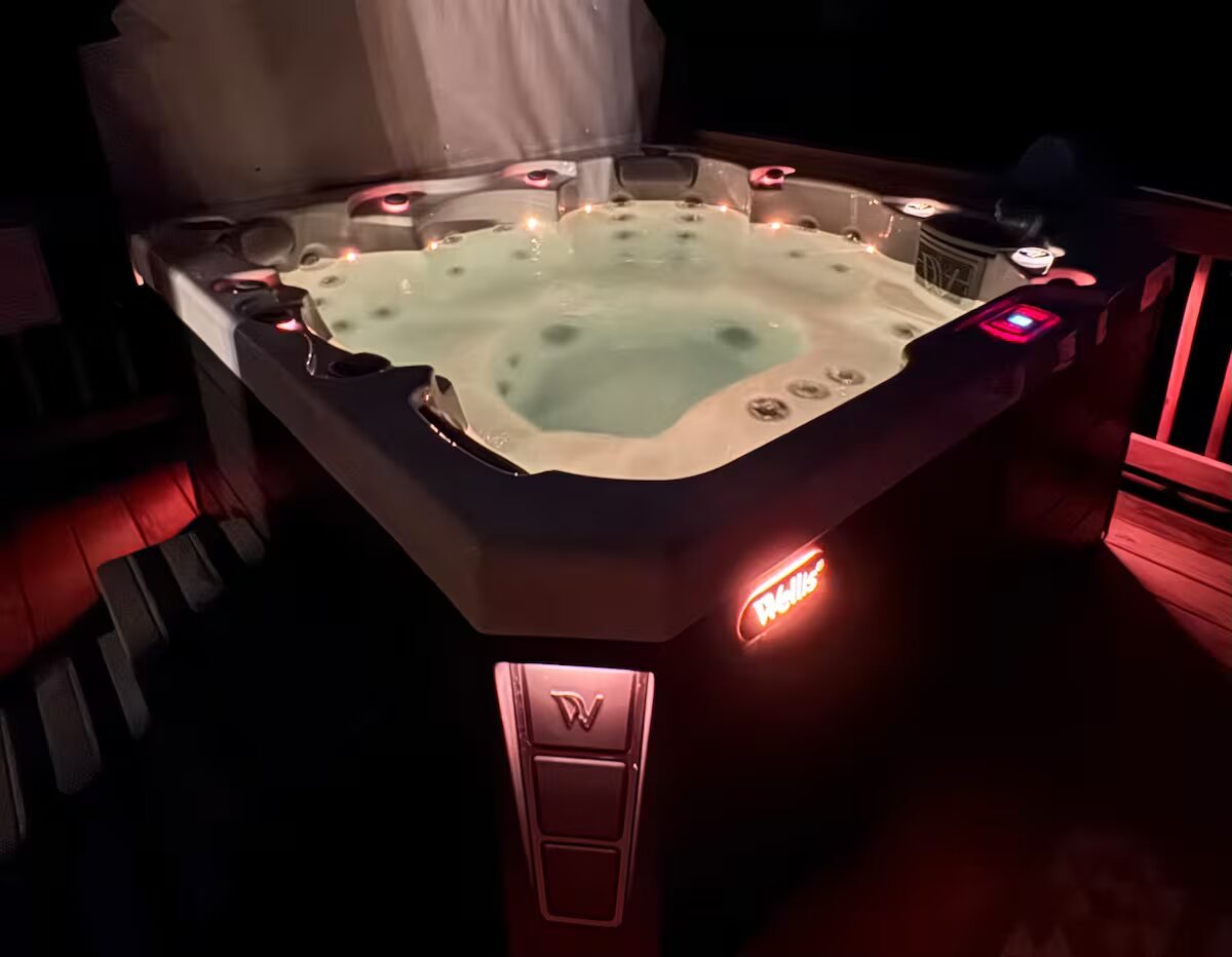 The private hot tub lit up at night on the deck